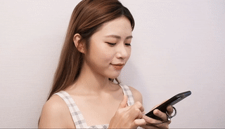 拿著智慧型手機的人在螢幕上滑動。他們留著長髮，穿著格子上衣。.