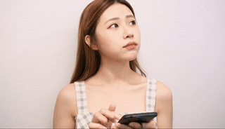 長髮、格子上衣的女人在樸素的背景下拿著智慧型手機，一邊看著一邊。.